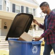 Man throwing box into tall recycling bin
